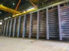 Large steel beams being lifted by a crane inside an industrial facility.