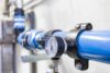 Close-up of a pressure gauge mounted on a blue industrial pipeline.
