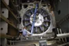 Top-down view of a large circular industrial mechanism being assembled by a worker in a factory setting.