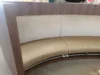 A curved seating booth with a wooden exterior, light beige cushioned seat, and a textured fabric backrest, showcasing a modern and comfortable design.
