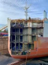 The rear section of the ship in a dry dock, with its stern exposed to reveal the interior compartments during repair or construction work.