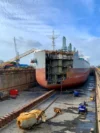 The rear view of the ship in dry dock, with the propeller detached and the rudder removed.