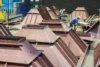 Workers inspecting and preparing large pyramid-shaped metal structures in an industrial workshop.