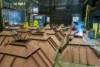 Workers are welding large pyramidal metal structures in an industrial workshop.