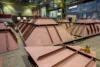 A group of large, pyramid-shaped metal structures lined up inside an industrial facility, with a lifting clamp tool resting on one of the structures in the foreground.