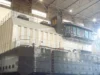A partially constructed ship with a large superstructure and control cabin in a shipyard.