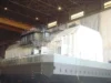 A large ship under construction in a shipyard, featuring a detailed superstructure and partially completed upper decks.