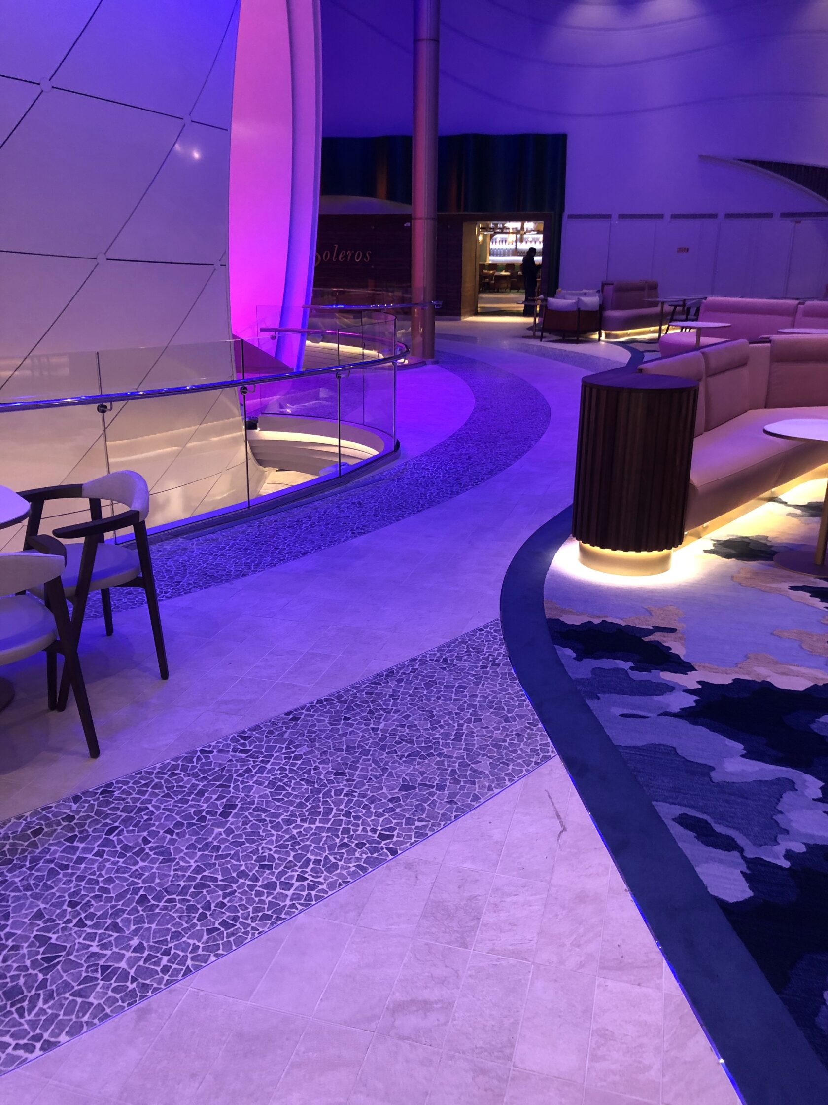 Modern interior with soft lighting, curved sofas, and glass railings, creating a cozy atmosphere.