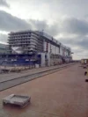 A large cruise ship under construction at a shipyard, with scaffolding and workers visible on multiple levels of the vessel.