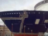 A close-up view of the bow of a partially constructed ship in a dry dock.