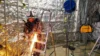 Worker using a grinder to cut metal, creating sparks inside a construction area with reflective insulation on the walls.
