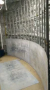 Curved metal framework partially covered with a sheet of material, in the process of interior construction against a reflective insulated wall.