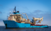Blue offshore vessel equipped with cranes and machinery, floating on the water.