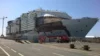 A large cruise ship under construction at a shipyard, with scaffolding and equipment surrounding it as work continues on the exterior.