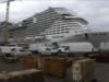 Large cruise ship MSC Meraviglia docked at a shipyard, surrounded by construction vehicles and equipment.