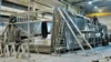 Shipbuilders working on the construction of a large ship's hull inside a shipyard, with scaffolding and ladders surrounding the structure.
