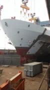 A ship's bow section being carefully lowered by cranes into place during the construction process in a shipyard.