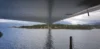 View from under a bridge spanning over water towards a green island.