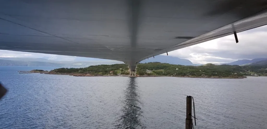 View from under a bridge spanning over water towards a green island.